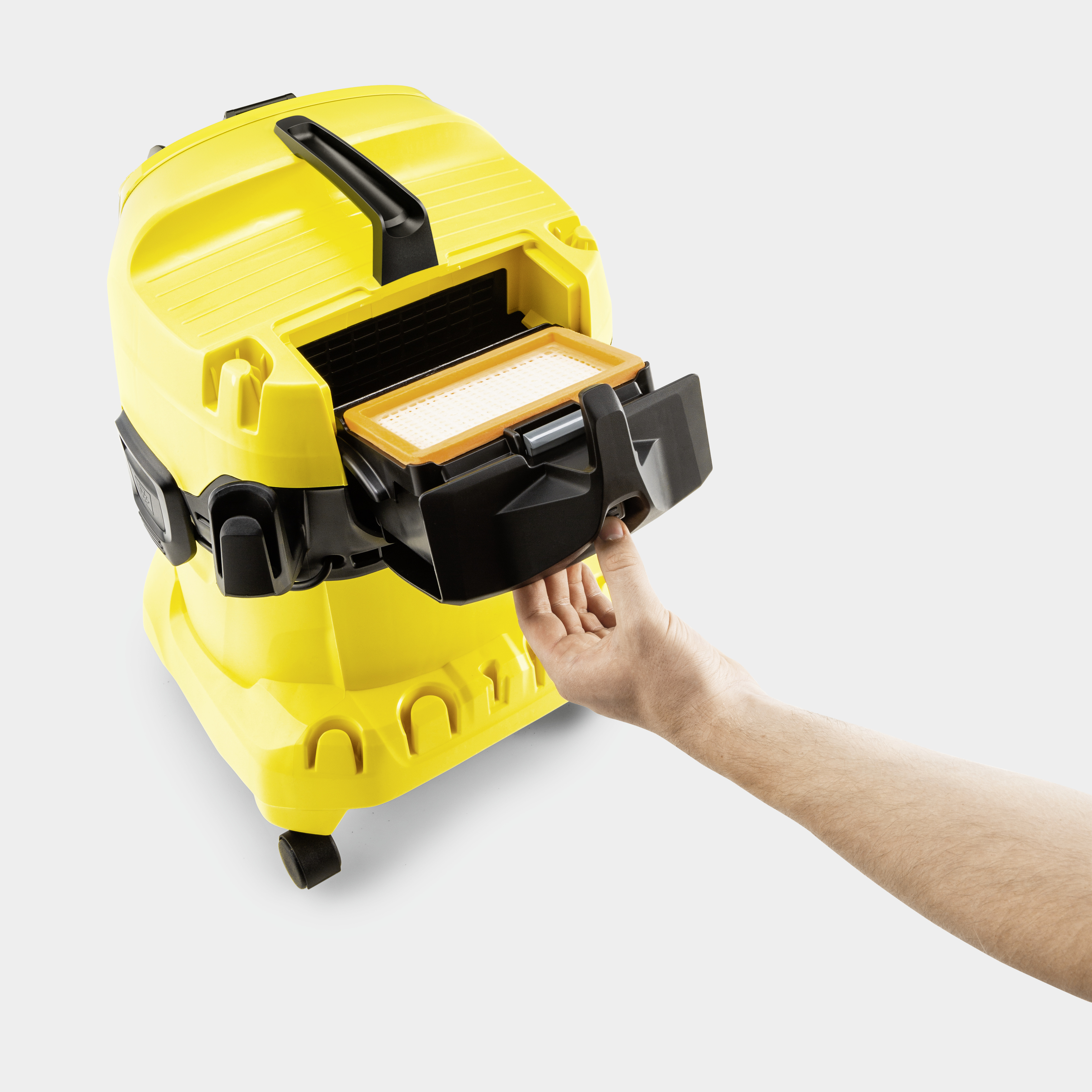 Una mano estrae il vano filtro di un aspirapolvere giallo.