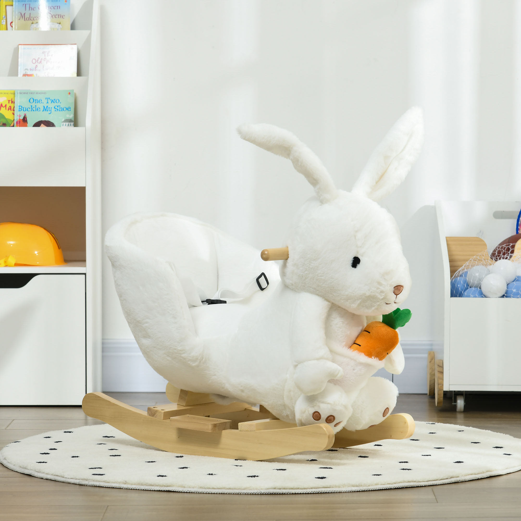 Un dondolo a forma di coniglietto bianco di peluche con carota e imbracatura su un tappeto a pois.