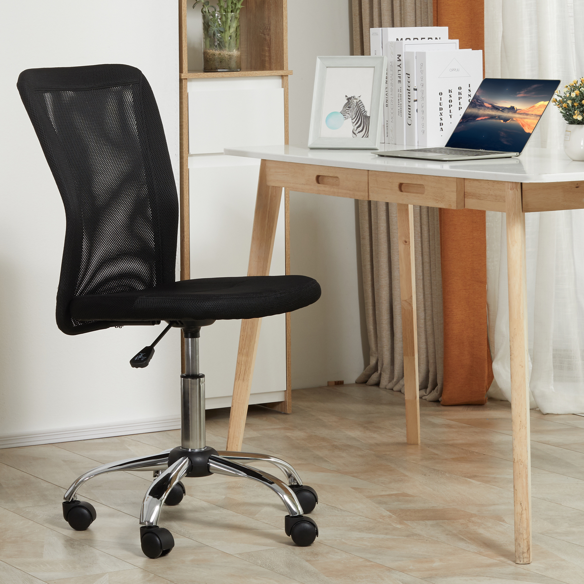 Una sedia da ufficio nera con ruote si trova davanti a una scrivania in legno con laptop.