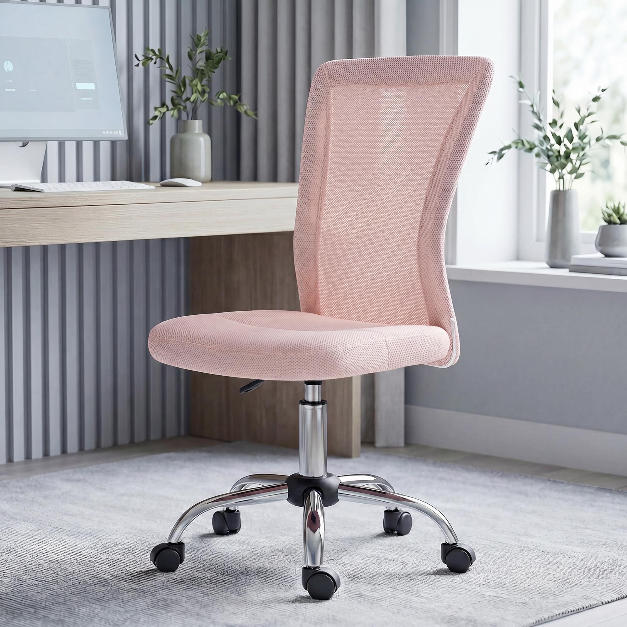Una sedia da ufficio in rete rosa si trova su un tappeto grigio davanti a una scrivania con computer.