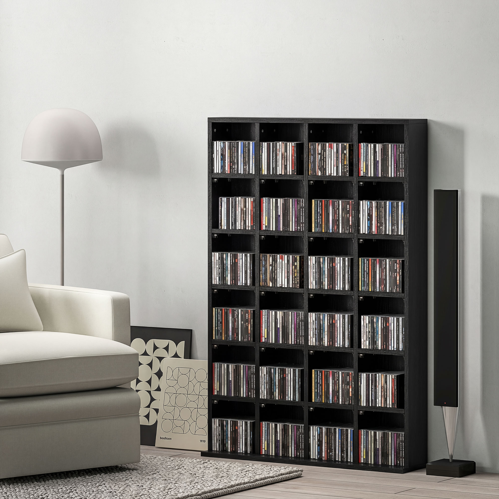 Un grande scaffale multimediale nero pieno di CD, affiancato da una lampada e un altoparlante in un soggiorno.
