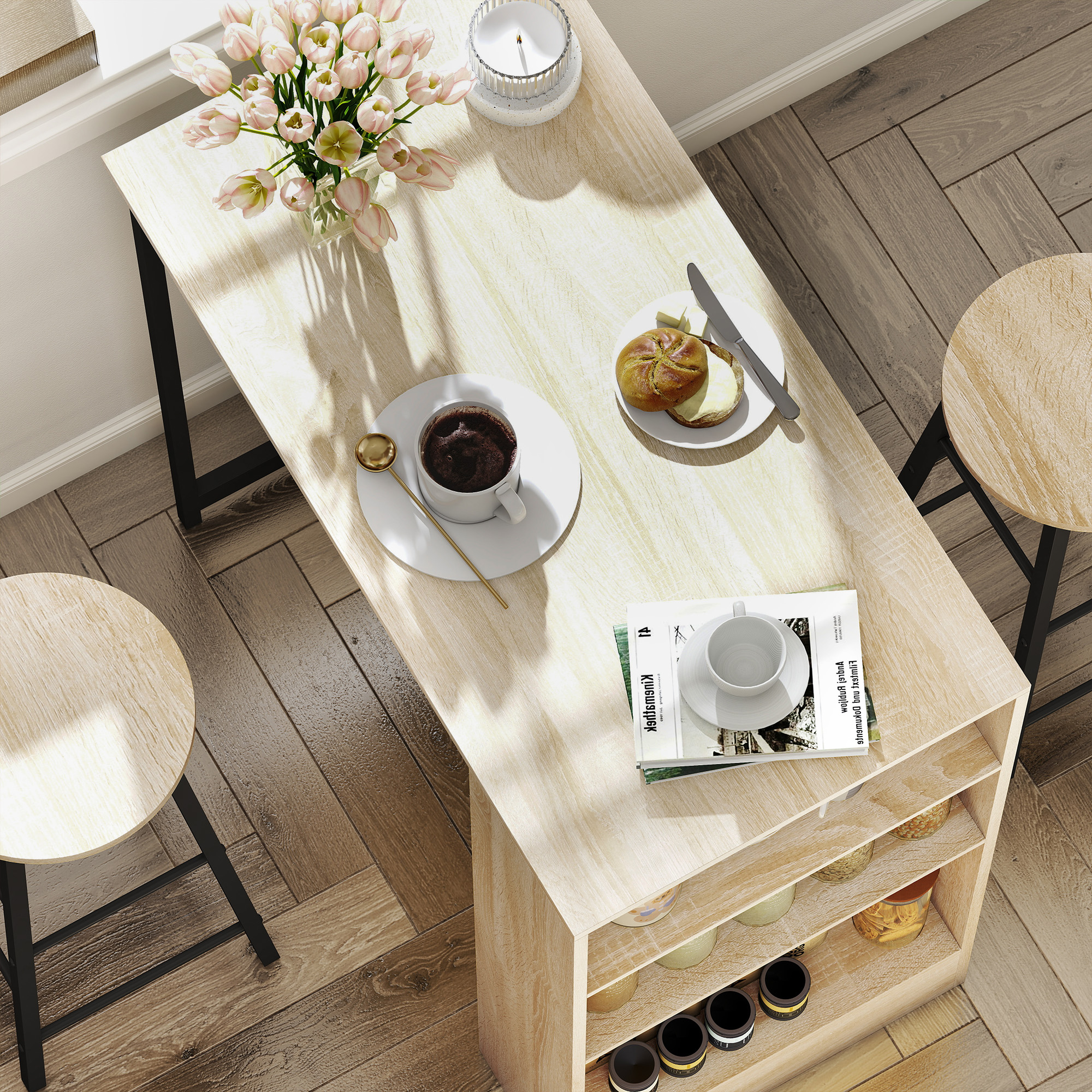 Mesa de madera con flores, café, panecillo y dos taburetes en suelo de madera.