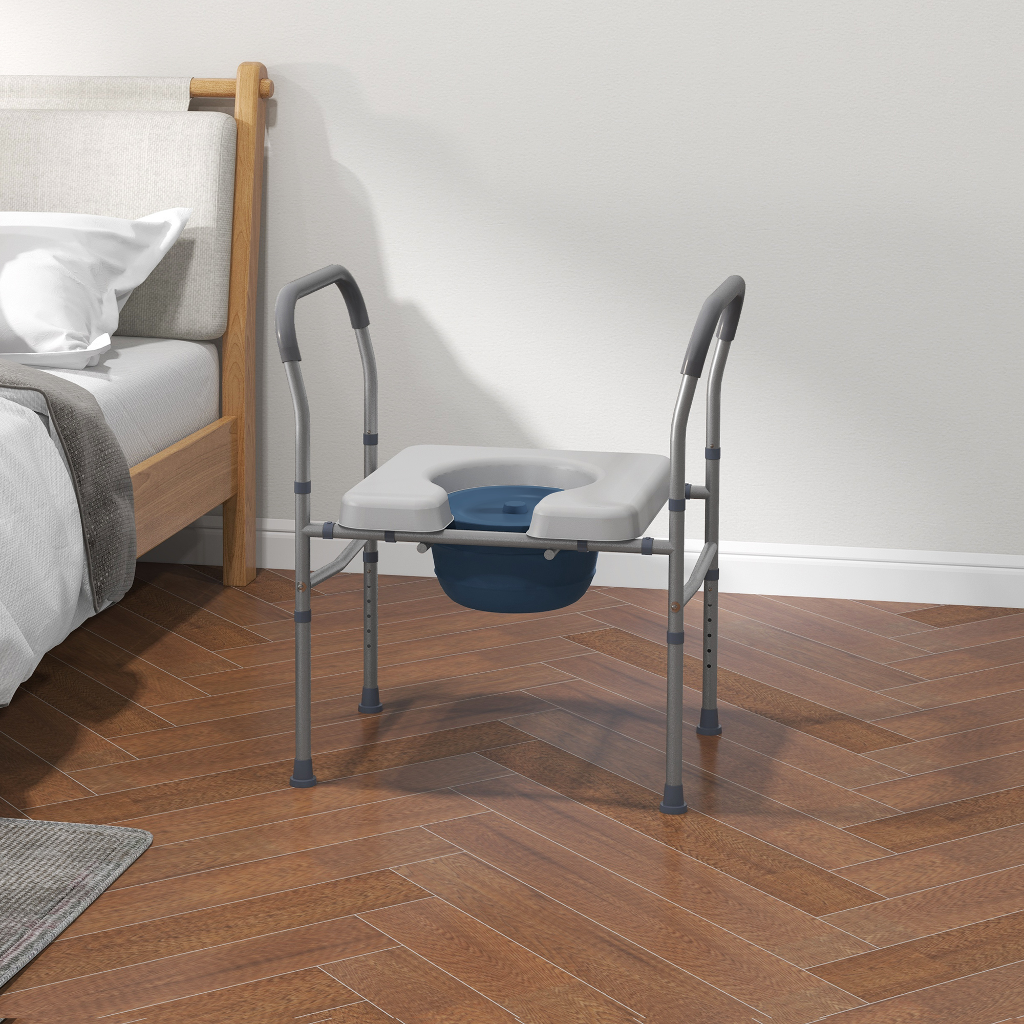 Silla inodoro de metal con asiento blanco y cubo azul sobre suelo de madera junto a una cama.