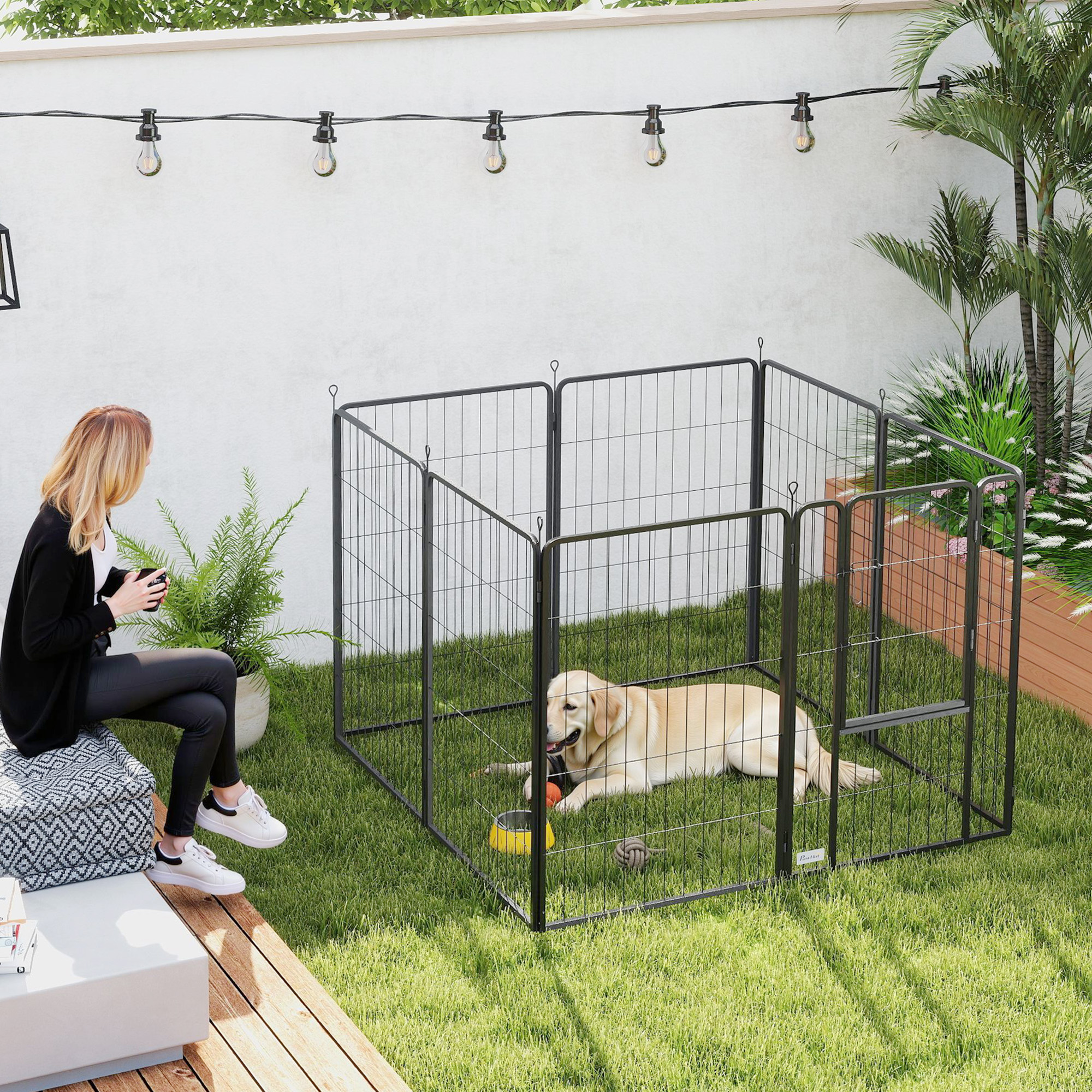 Una mujer se sienta afuera en un patio mientras un golden retriever yace dentro de un corral de metal en el césped.