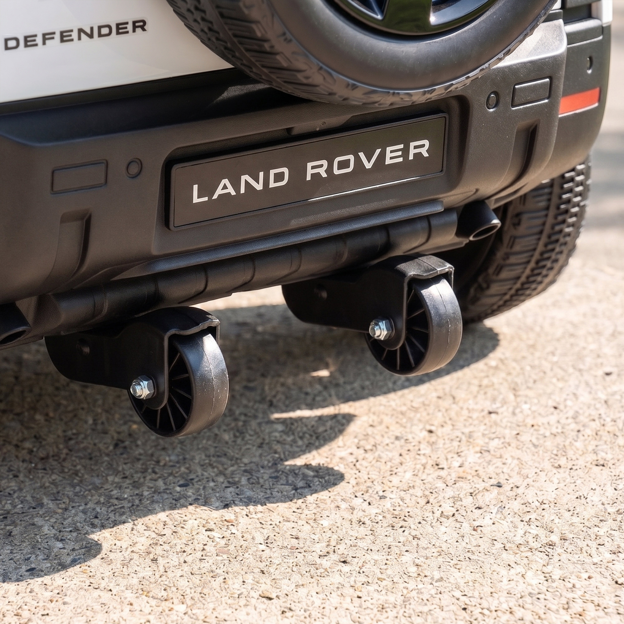 Parte trasera de un Land Rover Defender con dos pequeñas ruedas auxiliares montadas debajo en asfalto.