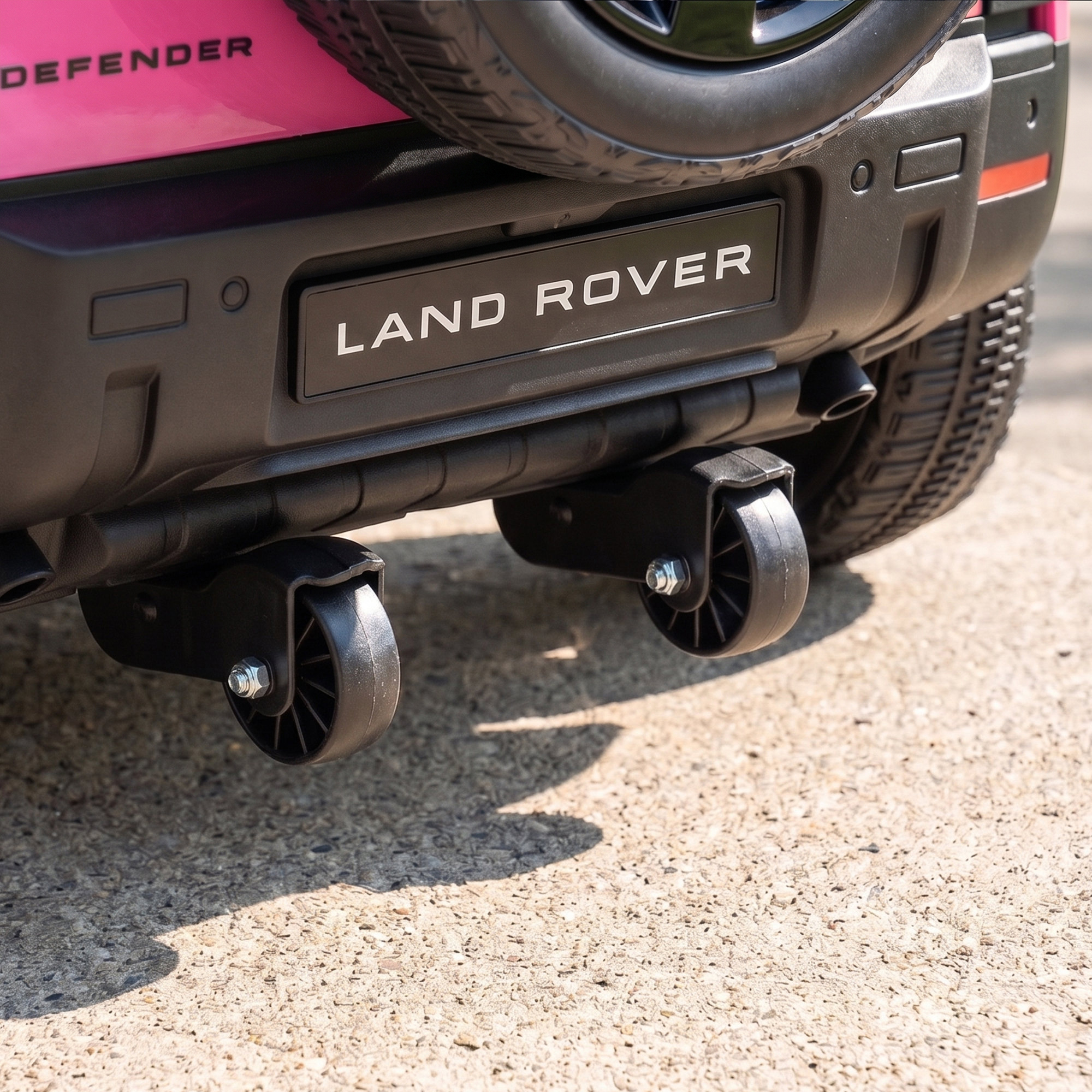 Parte trasera de un Land Rover Defender de juguete rosa con dos pequeñas ruedas giratorias negras debajo del parachoques.