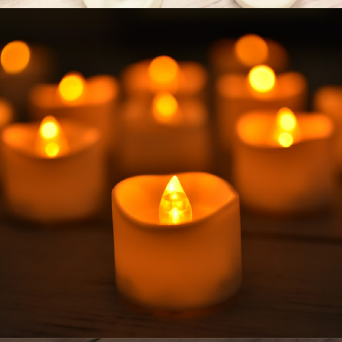 Eine Nahaufnahme brennender LED-Teelichter, die warmes Licht in einem dunklen Raum verbreiten.