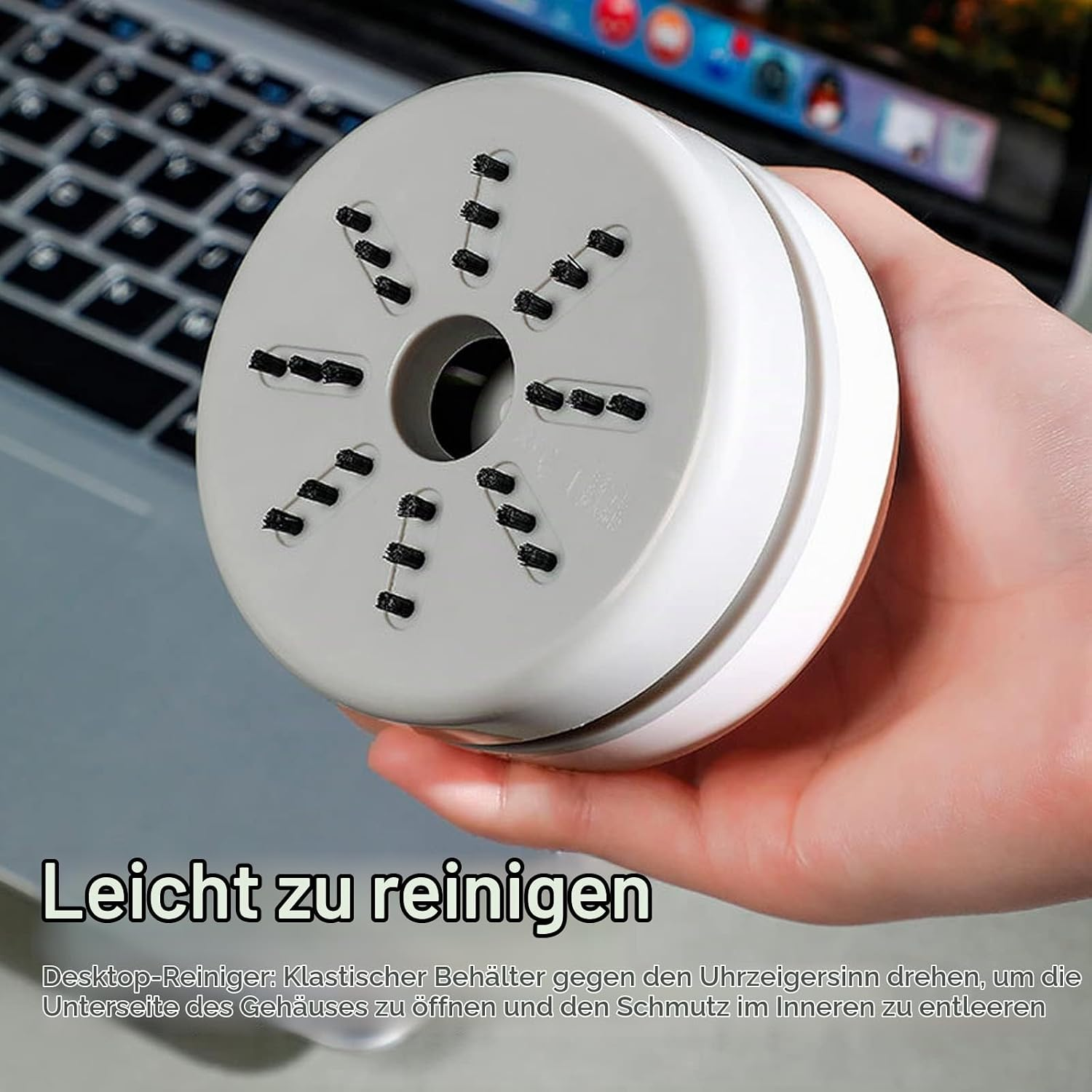Hand hält einen weißen und grauen Desktop-Reiniger mit kleinen schwarzen Borsten an der Unterseite.