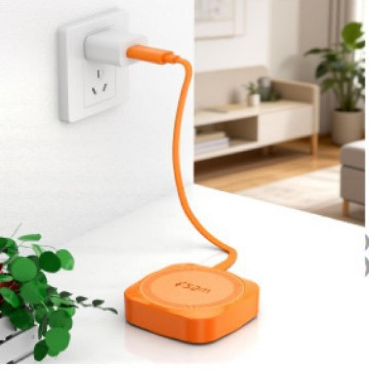Ein orangefarbenes Ladegerät auf einem weißen Tisch ist mit einem Adapter in einer Wandsteckdose verbunden.