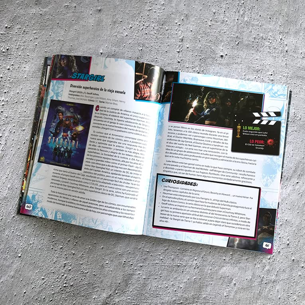 Una revista abierta con texto e imágenes sobre la serie Stargirl descansa sobre una superficie gris.