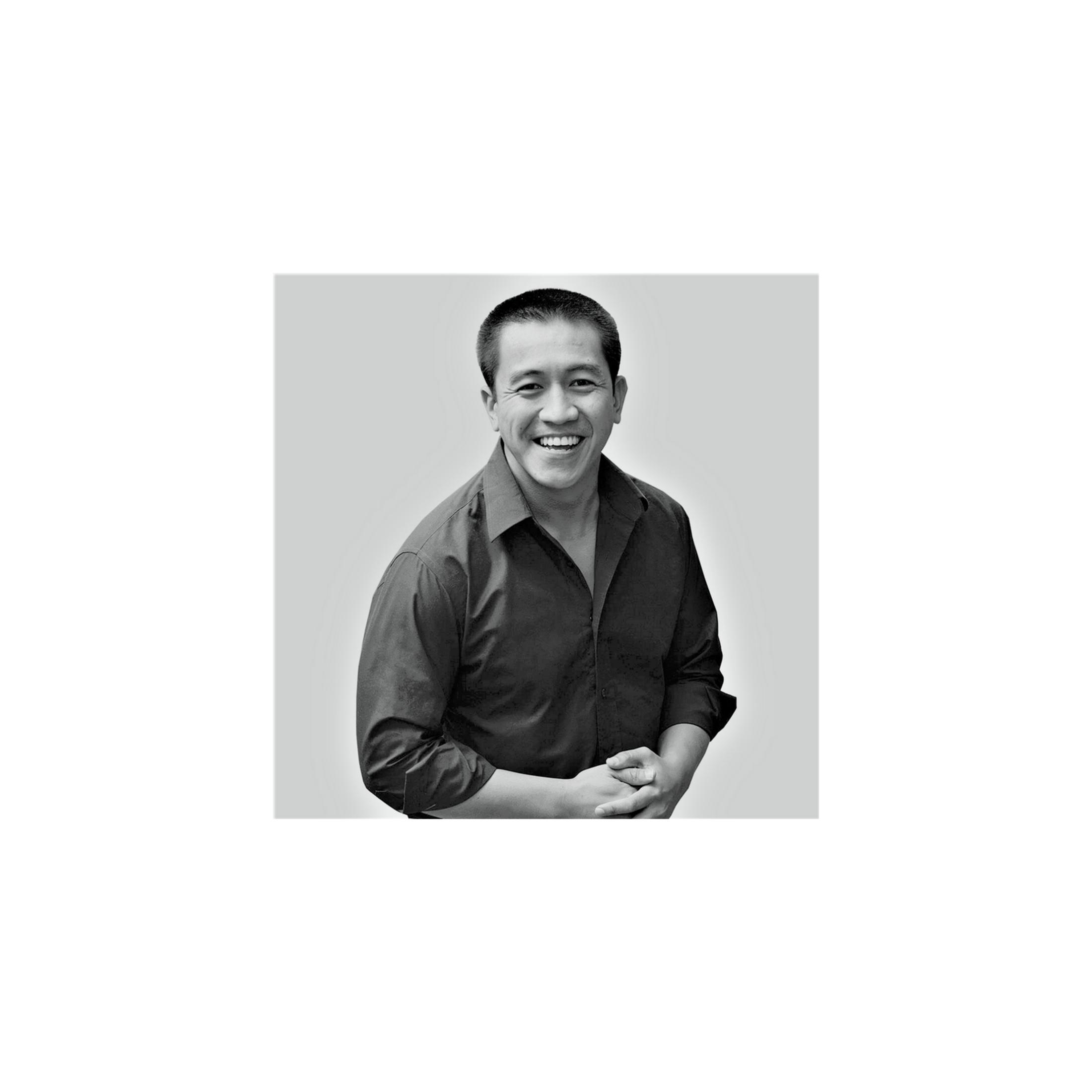 Retrato en blanco y negro de un hombre sonriente con camisa oscura sobre fondo claro.