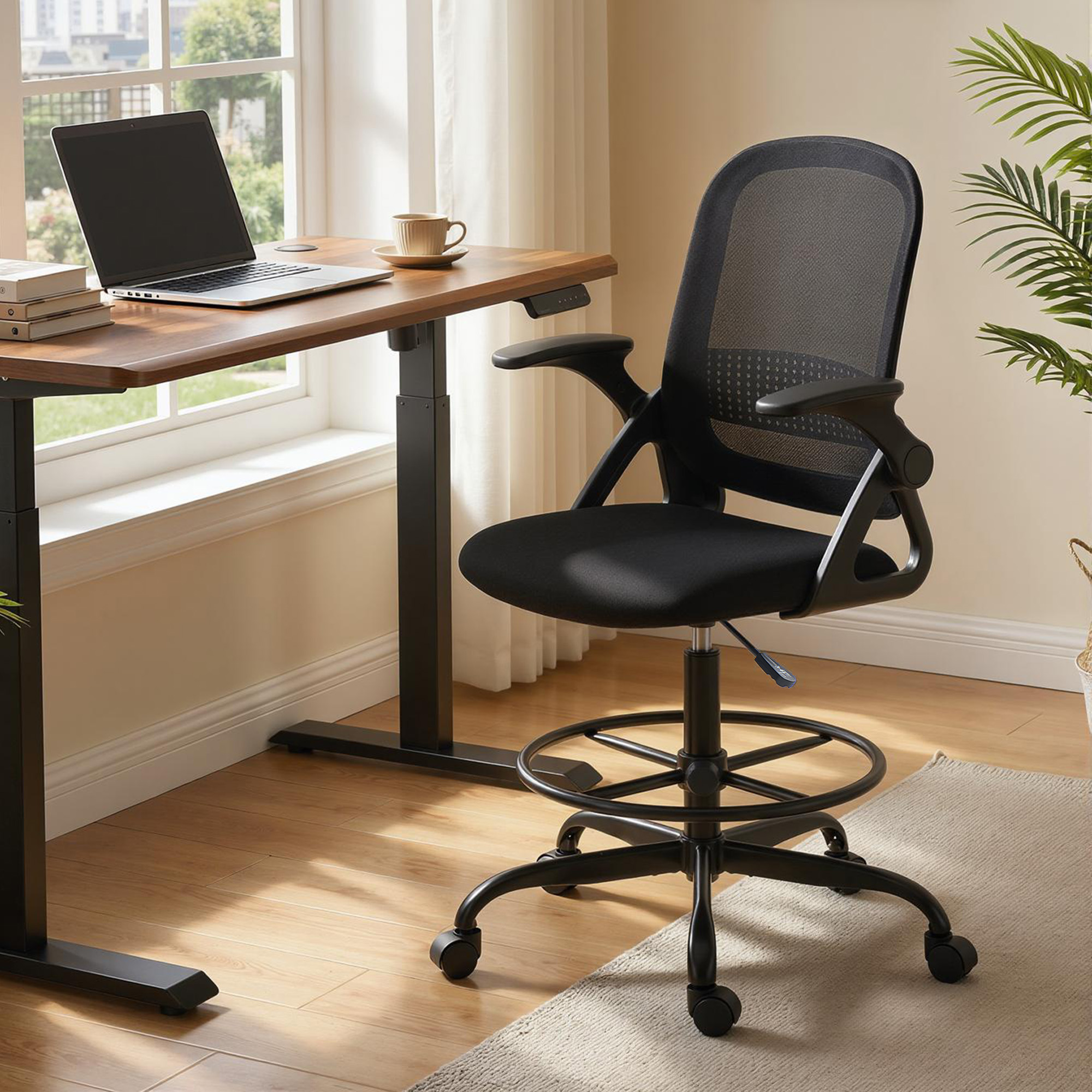 Una sedia da ufficio ergonomica nera con poggiapiedi davanti a una scrivania in legno con laptop.