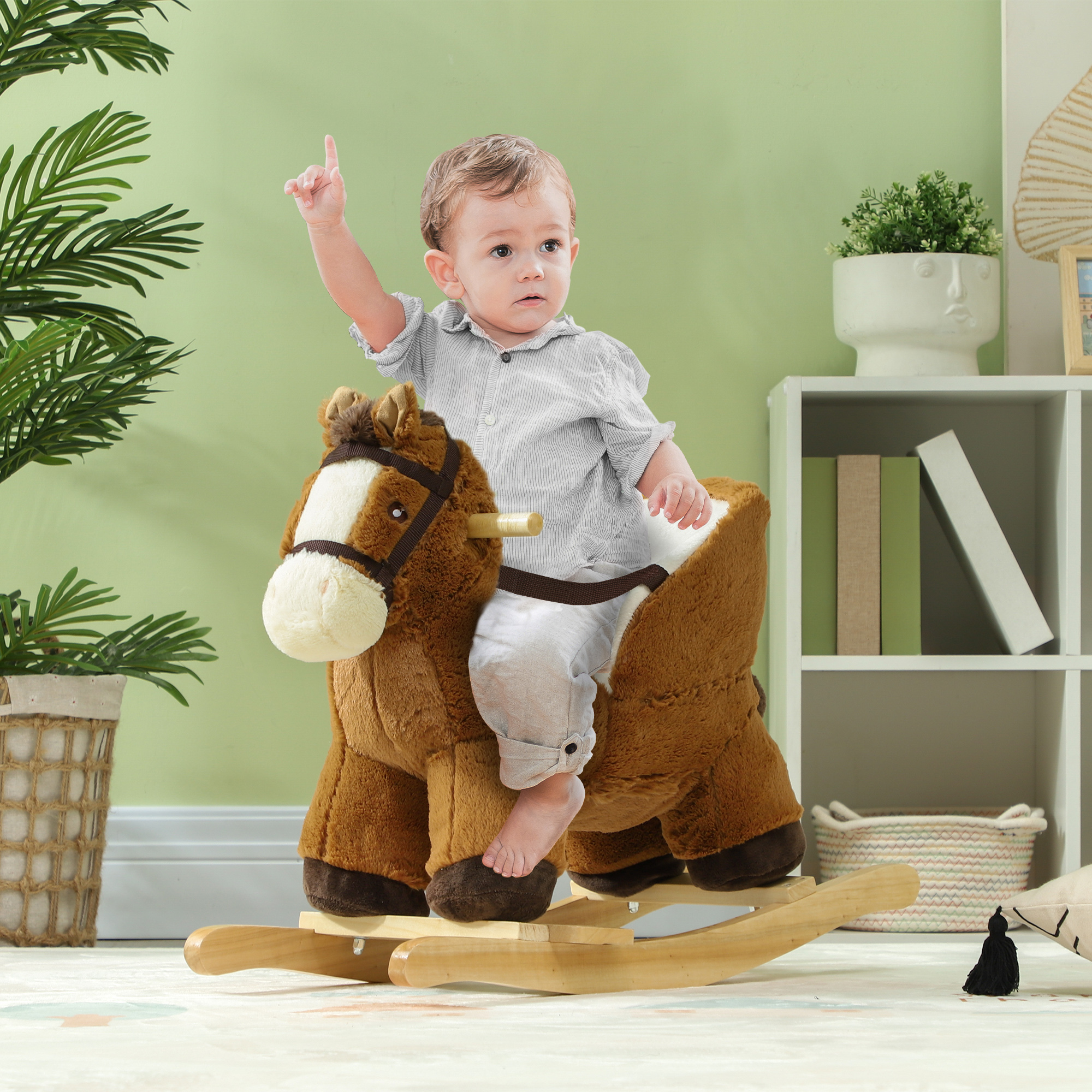 Un bambino piccolo siede su un cavallo a dondolo di peluche marrone, indicando con il dito.