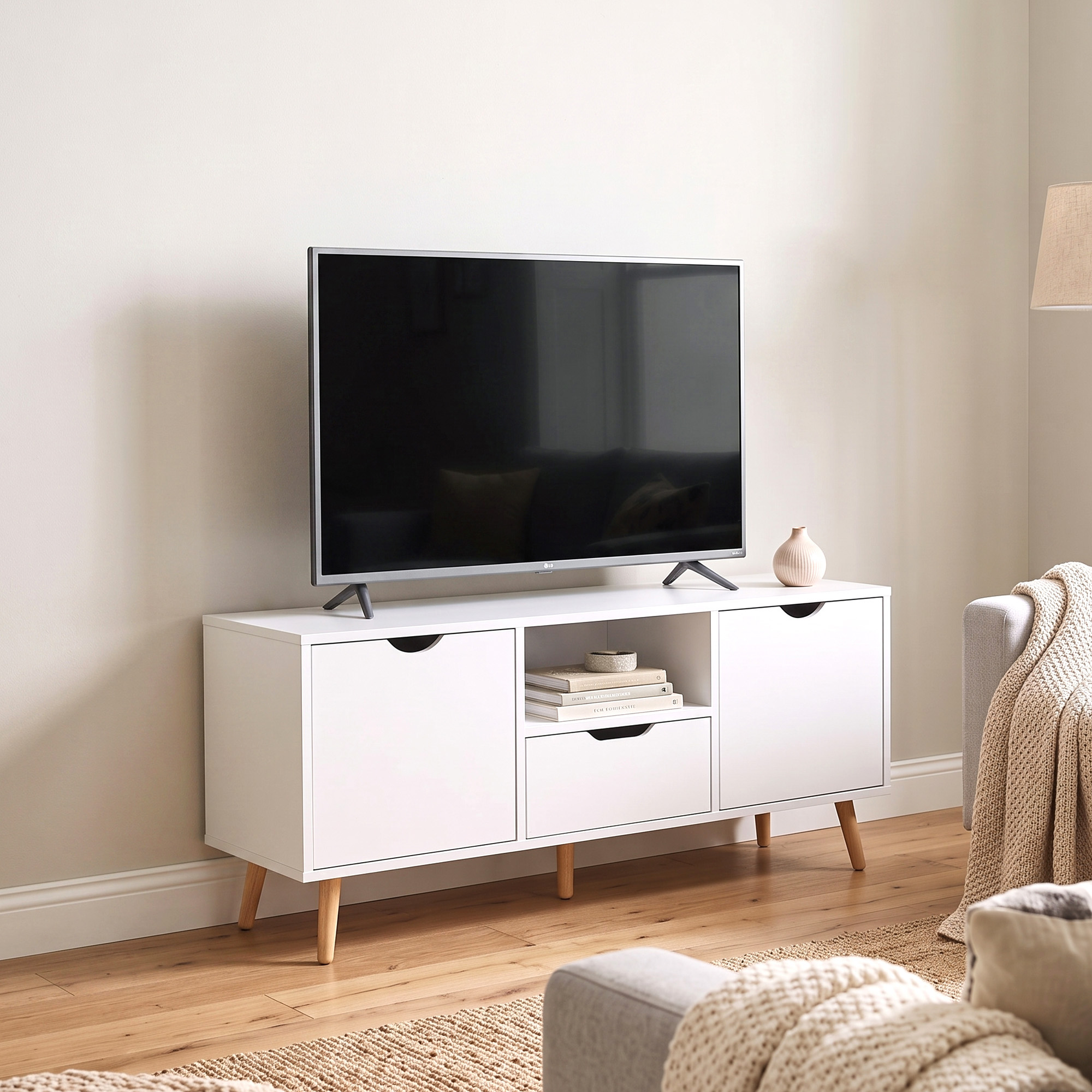 Un mobile TV bianco con gambe in legno e una televisione si trova in un soggiorno luminoso.