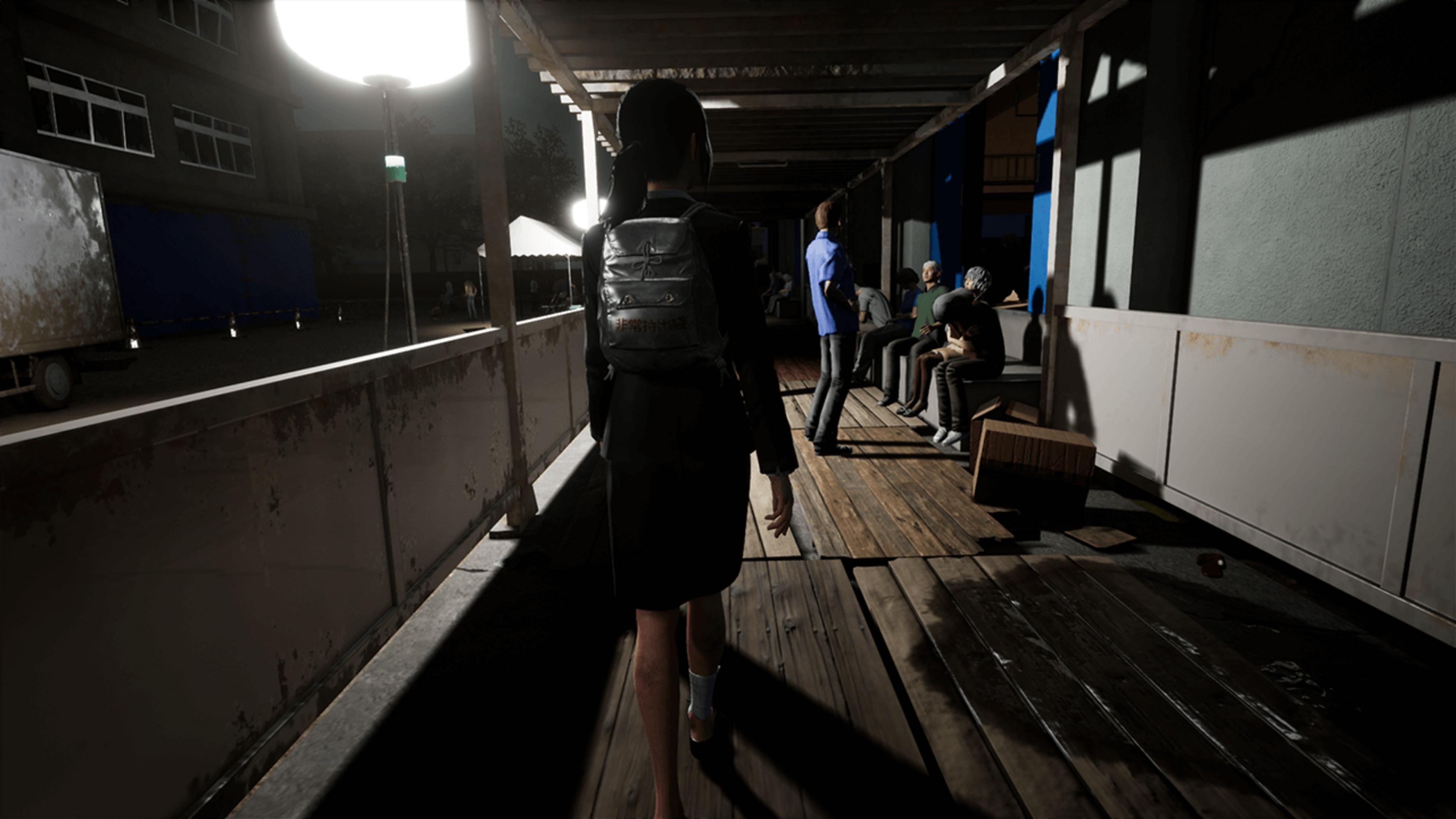 Une femme en vêtements sombres avec un sac à dos marche sur une passerelle en bois la nuit, d'autres personnes assises.