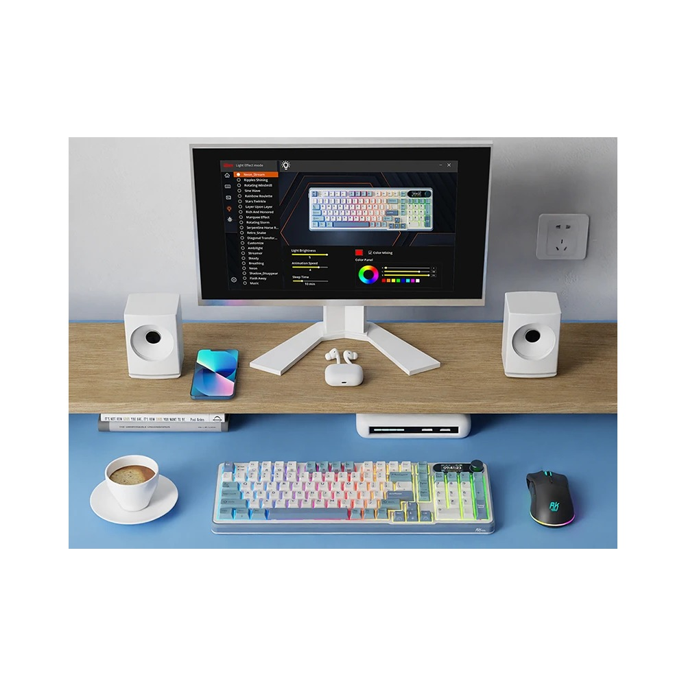 Nowoczesne biurko z monitorem, białą klawiaturą, głośnikami, kubkiem kawy i myszą RGB na niebieskim tle.