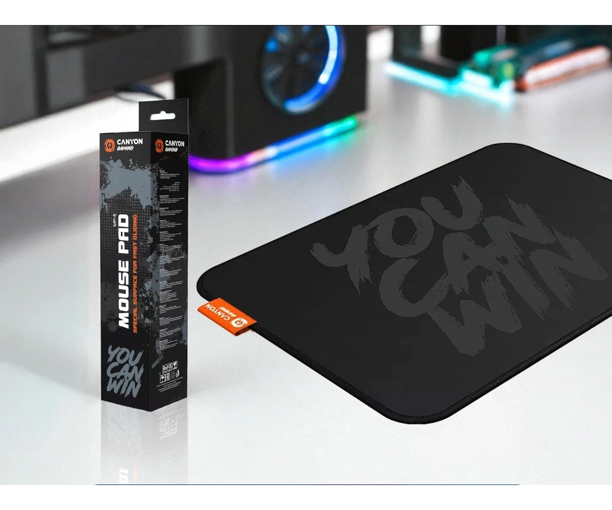 A black Canyon gaming mouse pad with packaging and the text You Can Win rests on a white desk.
