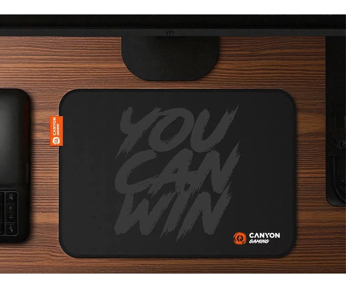 A black mouse pad with the text You Can Win and Canyon Gaming logo on a wooden desk.