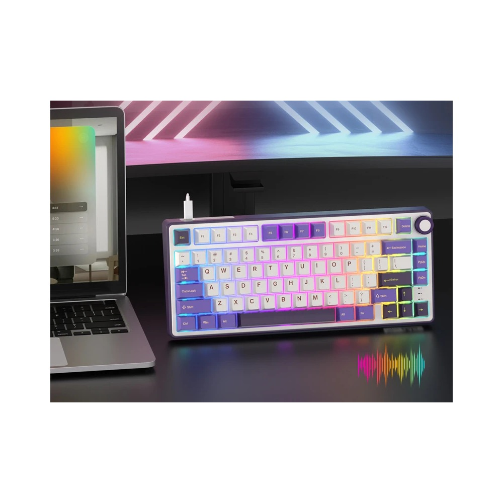 Kompaktowa, fioletowo-biała klawiatura mechaniczna z podświetleniem RGB obok laptopa na ciemnym biurku.