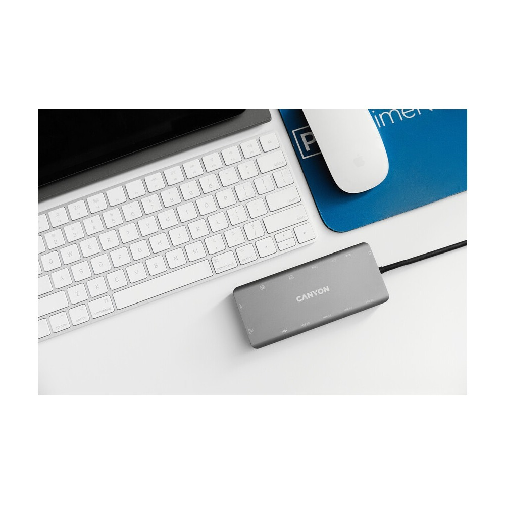 Szary hub USB Canyon na białym biurku obok białej klawiatury i myszy.
