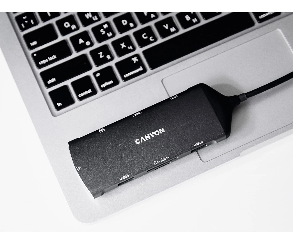 Czarny hub USB Canyon leży na klawiaturze laptopa.