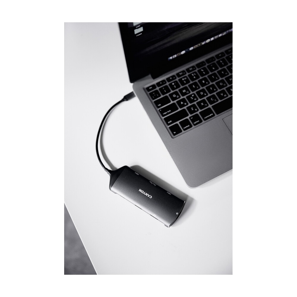 Hub USB-C Canyon jest podłączony do srebrnego laptopa na białym biurku.