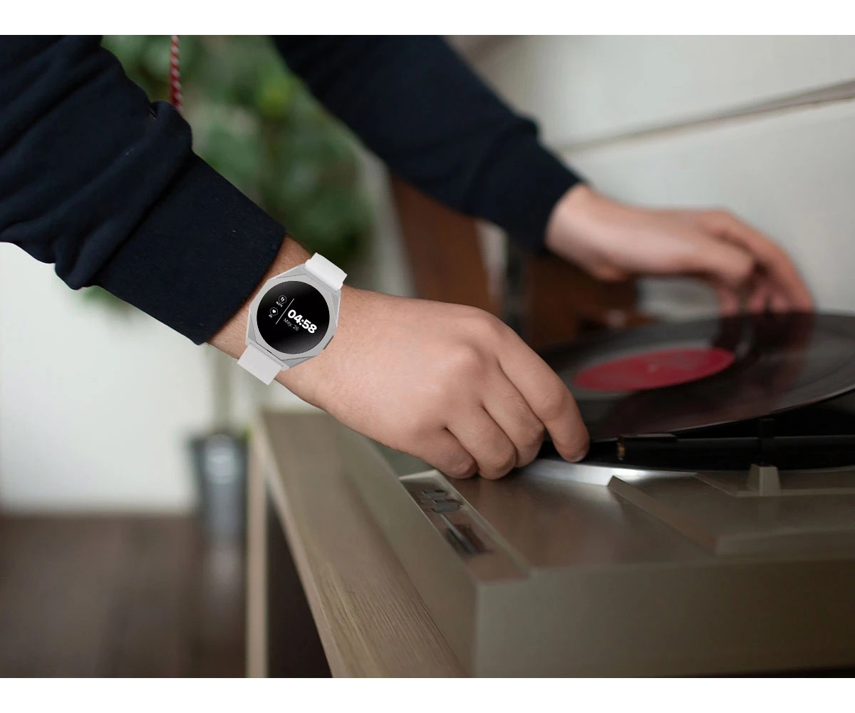 Osoba w białym smartwatchu kładzie płytę winylową na gramofon.