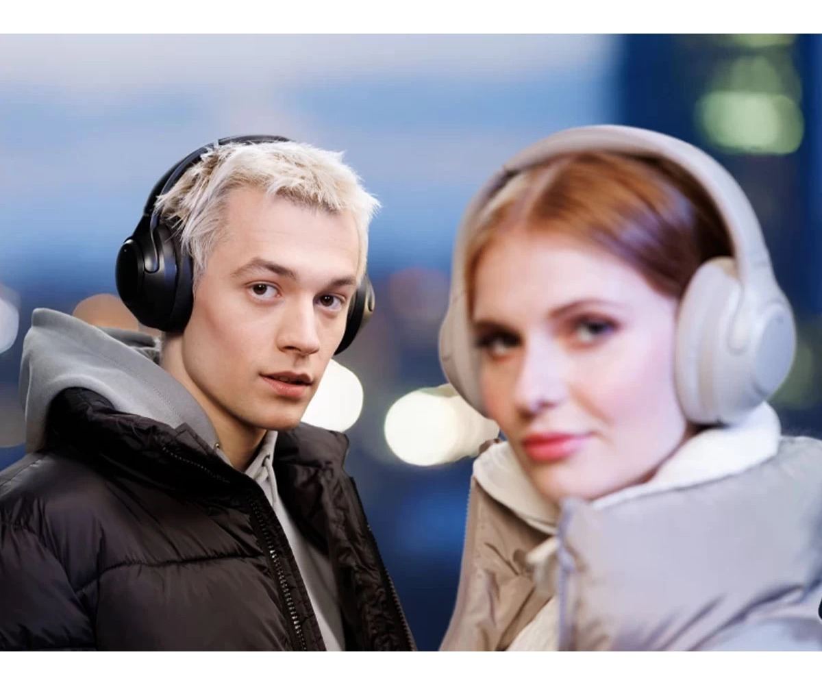 Mężczyzna o blond włosach i kobieta w słuchawkach bezprzewodowych na tle rozmytego miasta.