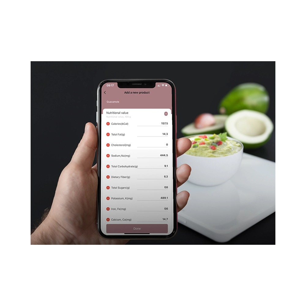 Smartfon pokazujący wartości odżywcze guacamole w dłoni, z miską guacamole i awokado w tle.