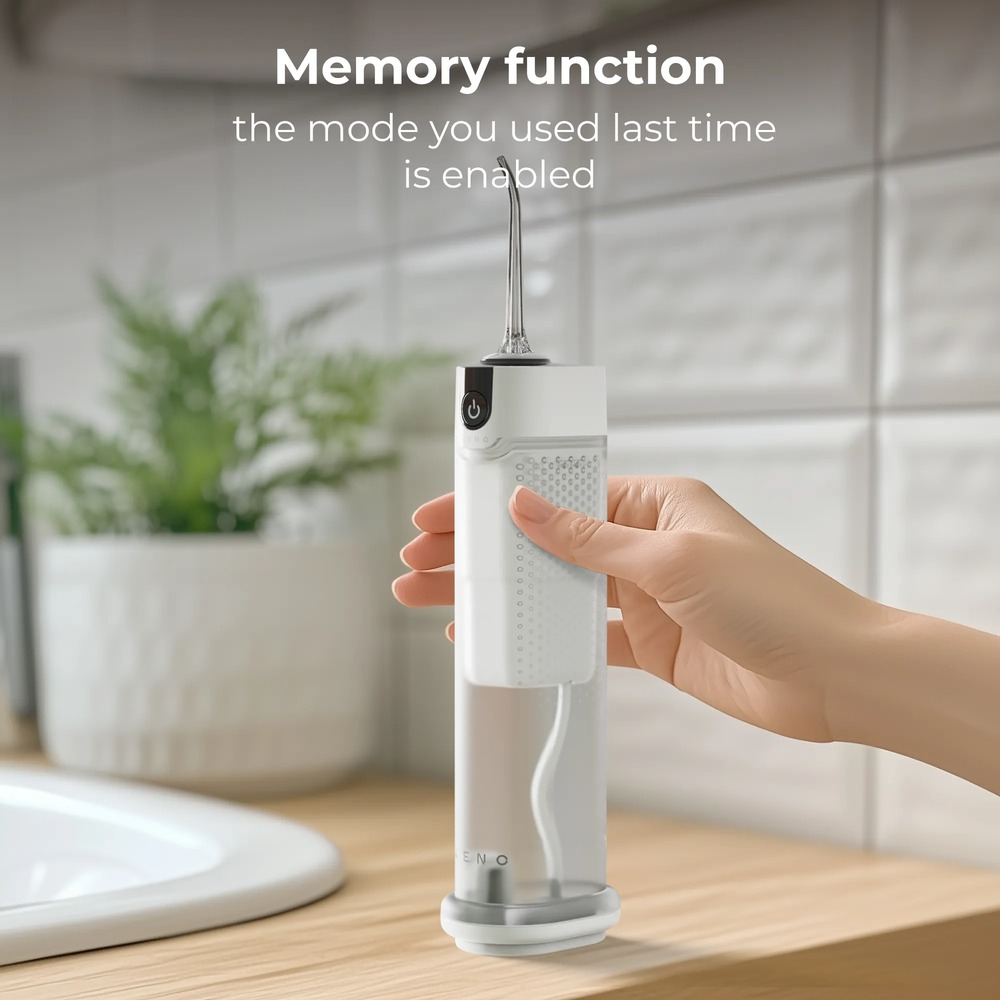 Una mano tiene un idropulsore portatile bianco su un mobile da bagno con pianta.