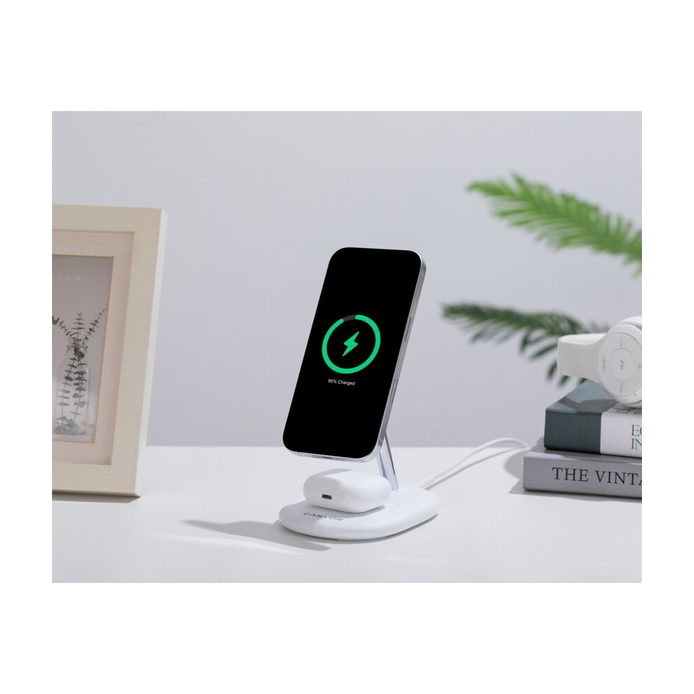 Biała bezprzewodowa stacja ładująca ładuje smartfon i słuchawki na stole.