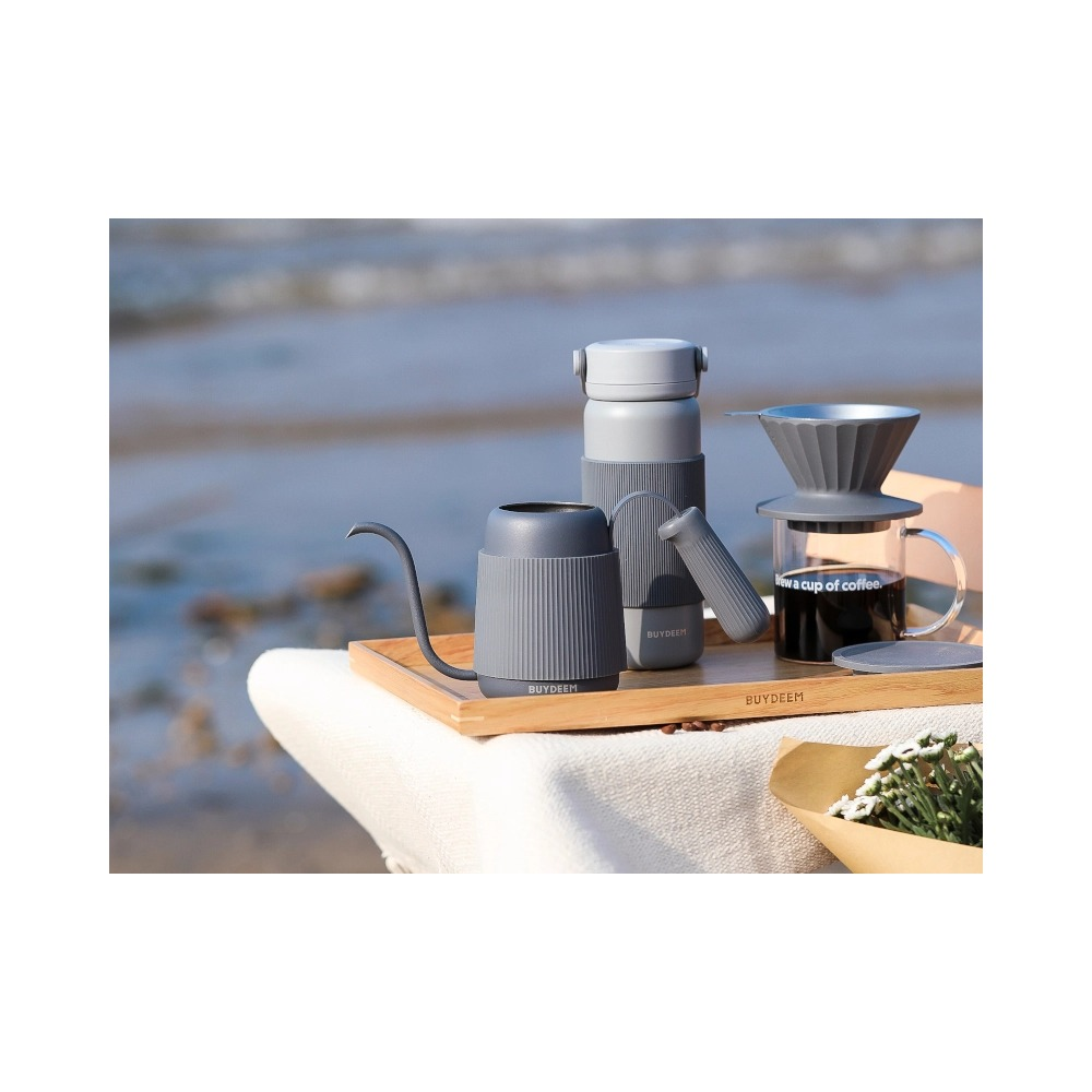 Set caffè grigio con bollitore, thermos e gocciolatore su vassoio di legno all'aperto.