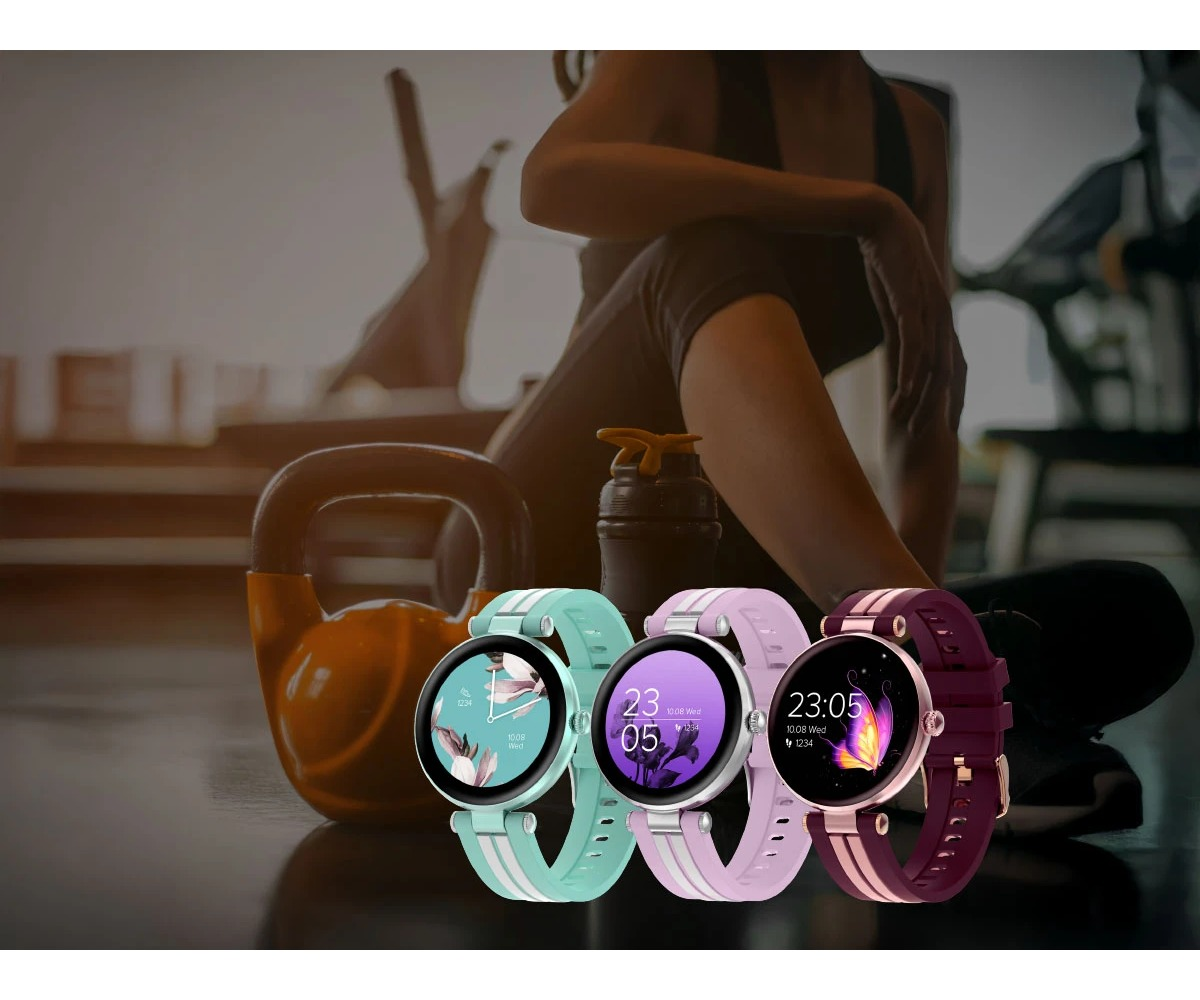 Trzy kolorowe smartwatche w kolorze miętowym, różowym i ciemnoczerwonym na tle fitness.