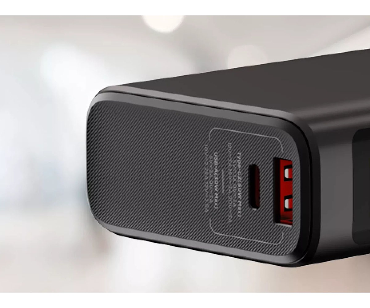 Zbliżenie ciemnoszarego powerbanka z portem USB-C i czerwonym USB-A na teksturowanym panelu przednim na rozmytym tle.