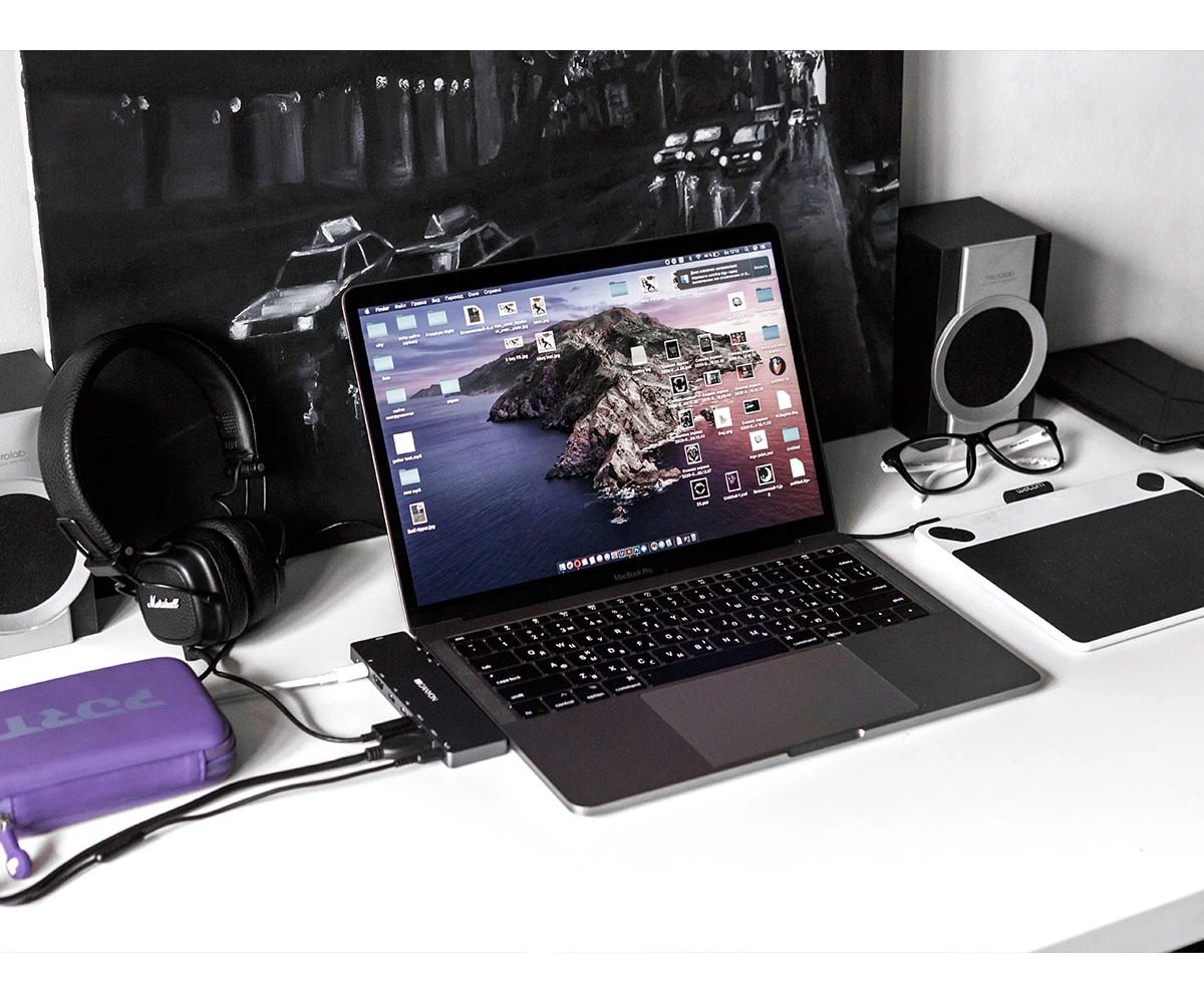 Laptop na biurku ze słuchawkami, głośnikami, tablet graficzny i okularami.