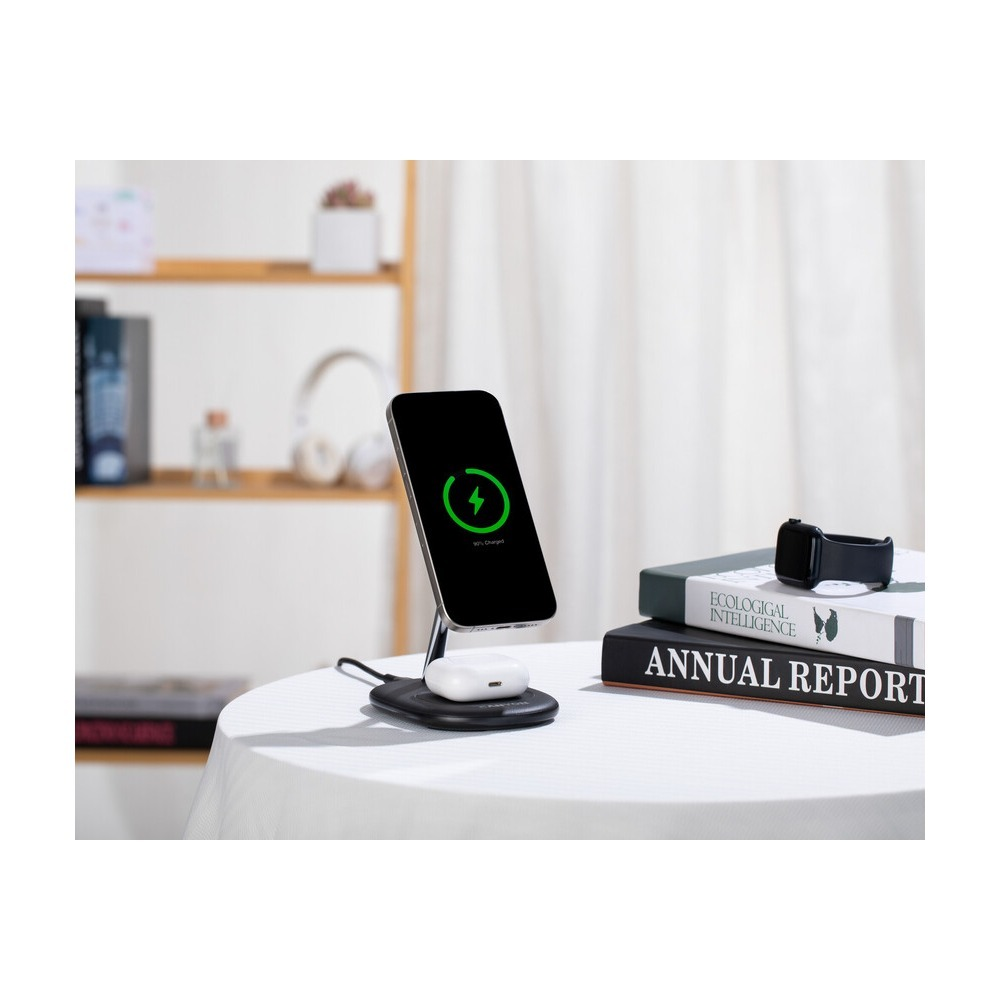 Smartfon i słuchawki ładowane bezprzewodowo na stole obok książek w jasnym pokoju.