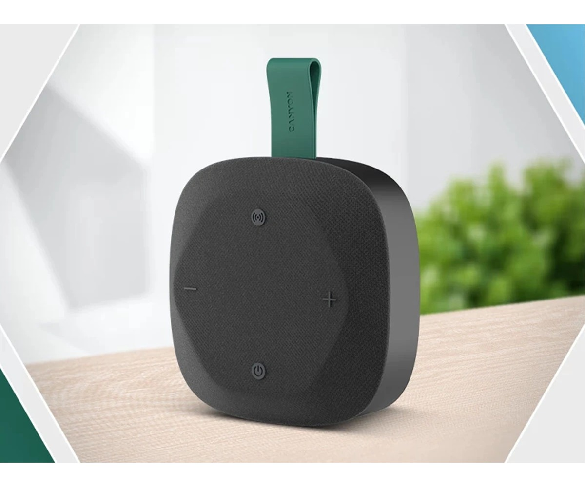 Czarny, kwadratowy głośnik bluetooth z zielonym paskiem stoi na drewnianej powierzchni.
