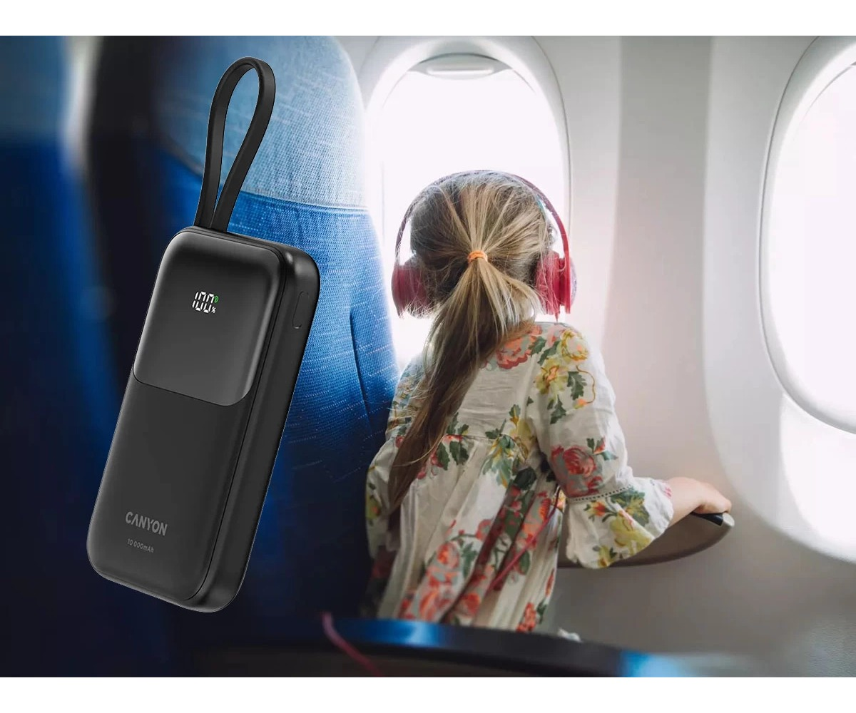 Czarny powerbank Canyon na pierwszym planie, a dziecko w słuchawkach patrzy przez okno samolotu.