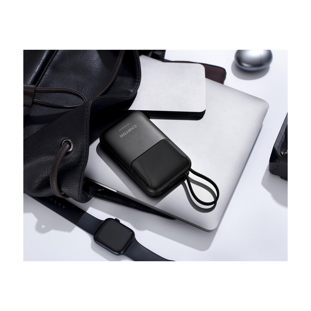 Czarny powerbank Canyon, laptop, torba i smartwatch na białej powierzchni.