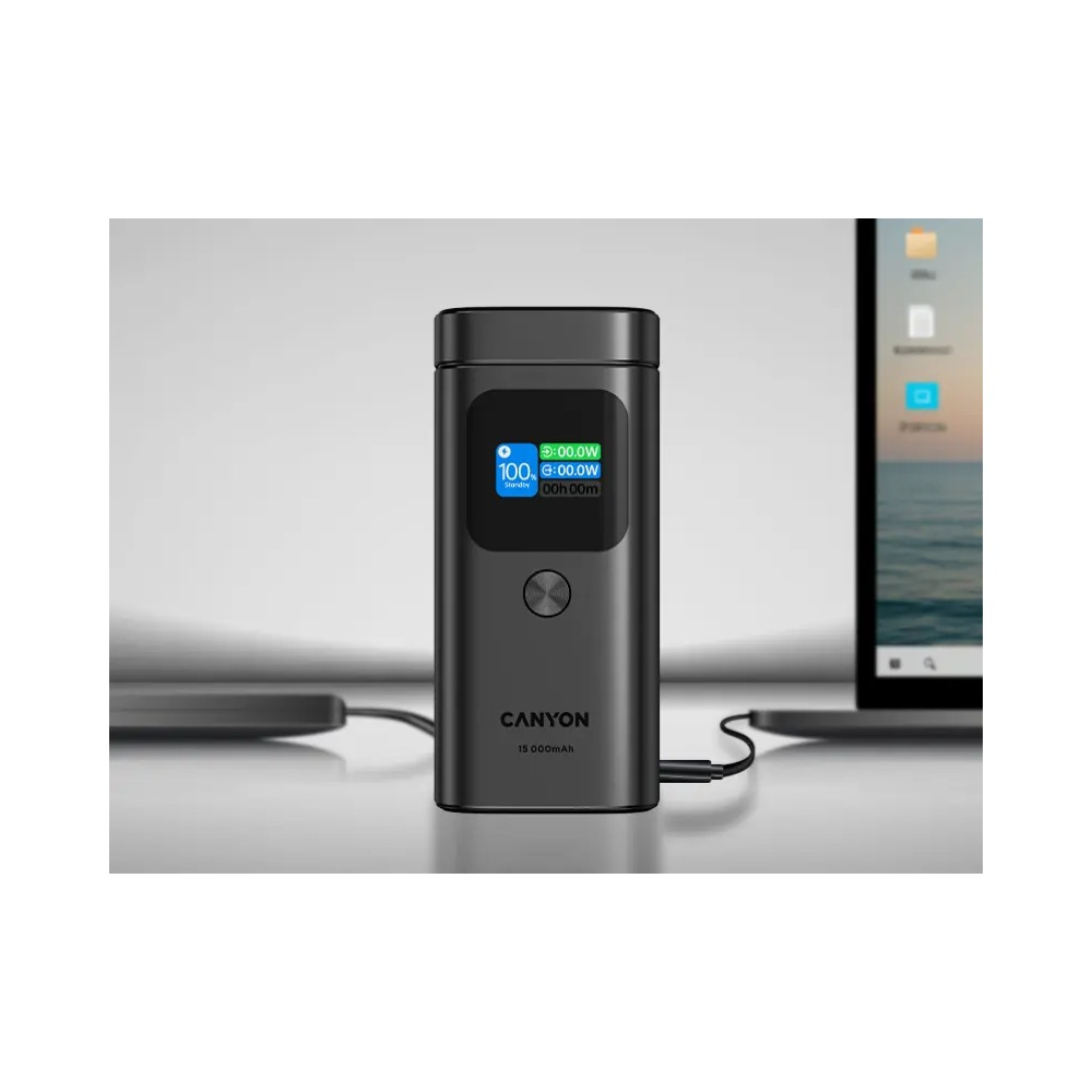 Czarny powerbank Canyon z cyfrowym wyświetlaczem, podłączony do laptopa na biurku.