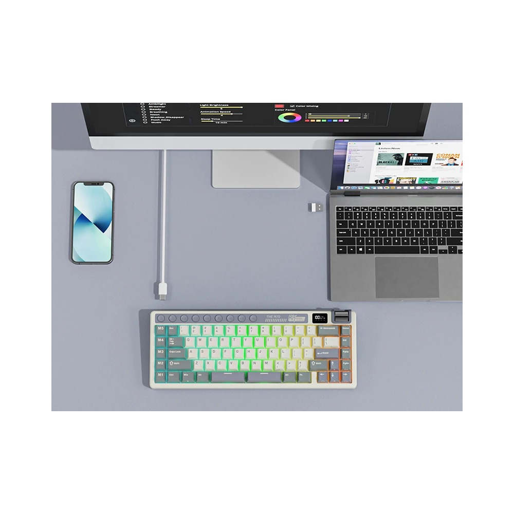 Biurko z monitorem, laptopem, smartfonem i kolorowo podświetlaną klawiaturą.
