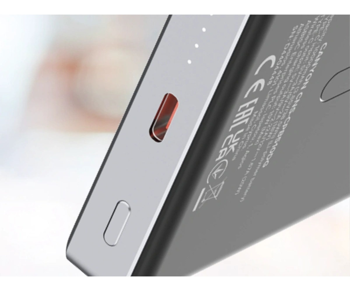 Zbliżenie srebrnego powerbanku z portem USB-C, kontrolkami i tekstem.