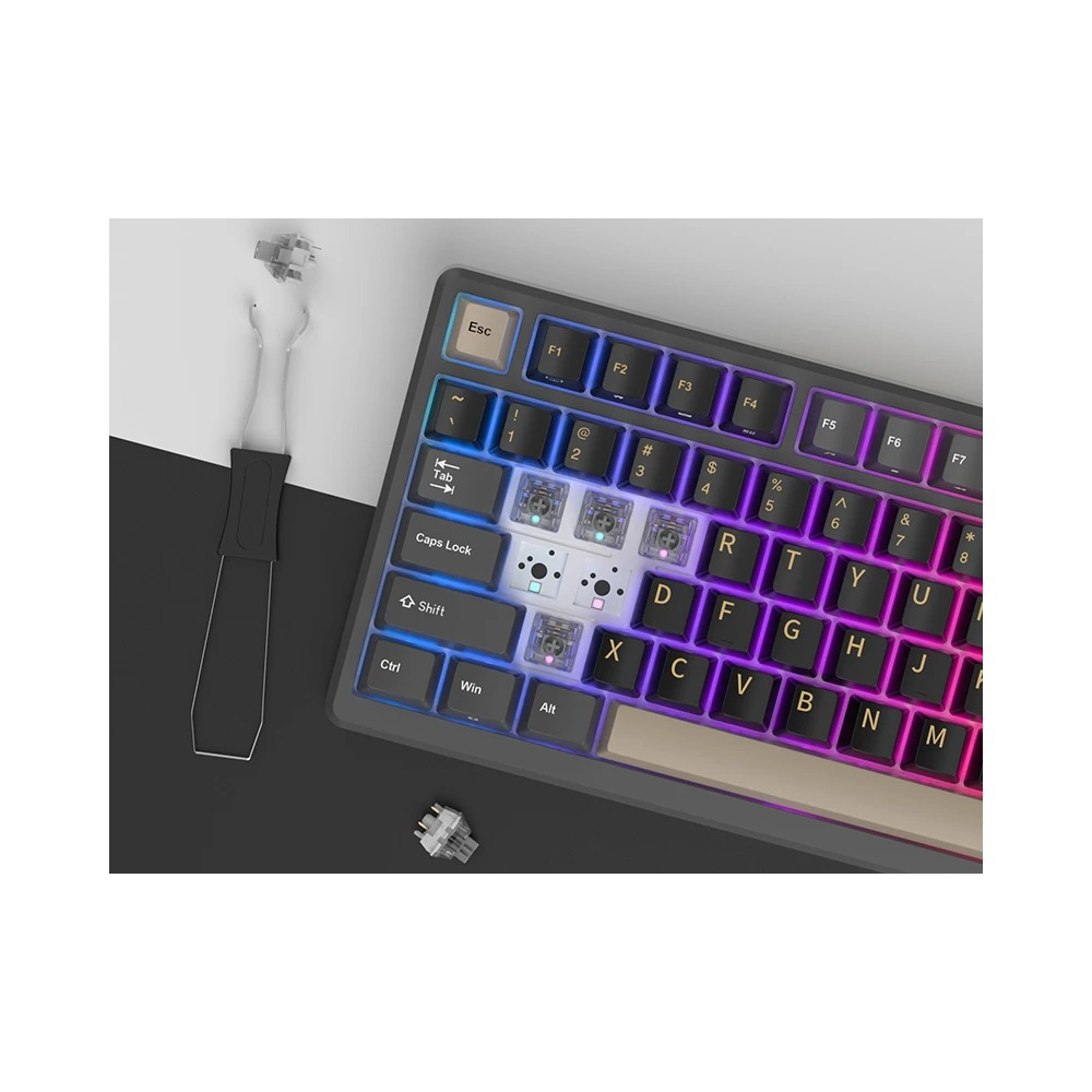 Un teclado mecánico con teclas removidas, mostrando interruptores, junto con un extractor y dos interruptores.