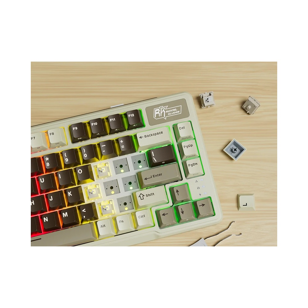 Beżowo-brązowa klawiatura mechaniczna z podświetleniem RGB, usuniętymi nakładkami klawiszy i przełącznikami na stole.