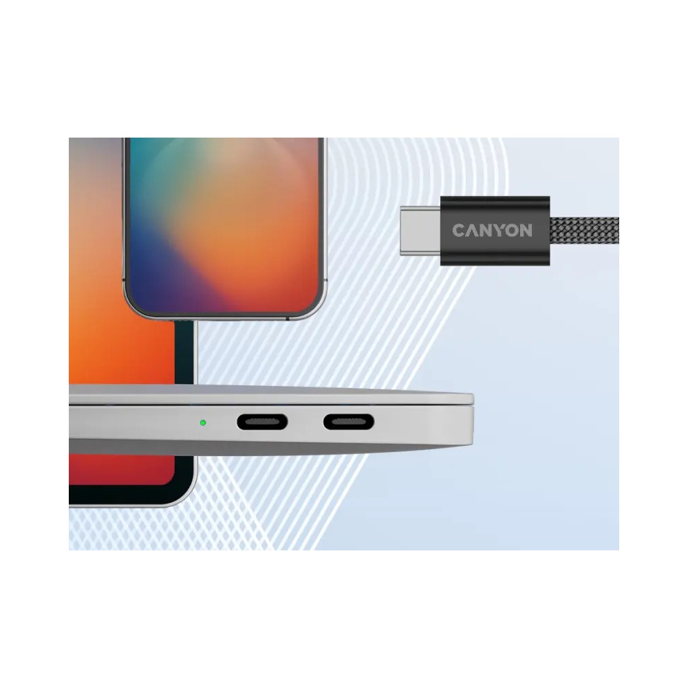 Kabel USB-C marki Canyon zbliża się do portów laptopa, w tle widoczne są ekrany.