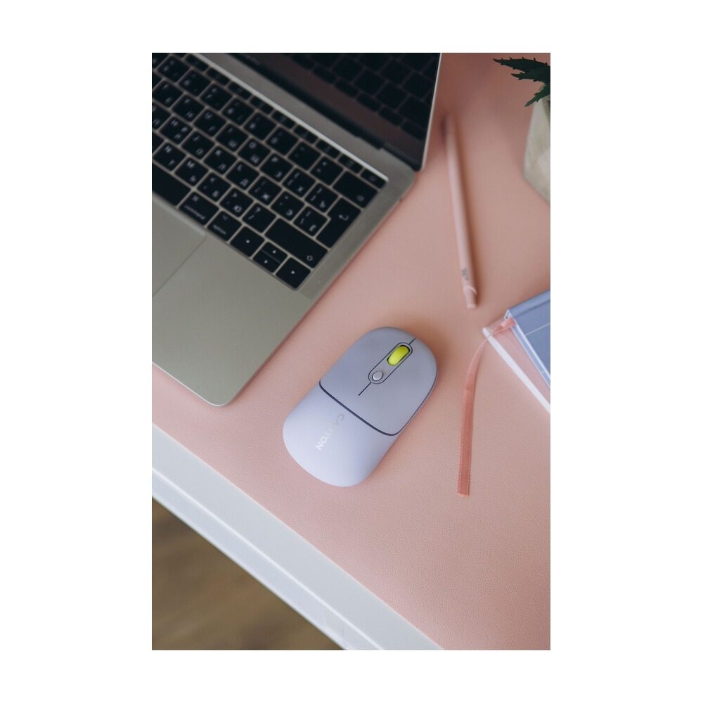 A light purple computer mouse with a yellow scroll wheel on a pink desk mat next to a laptop.