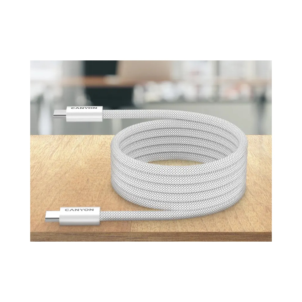 Biały, wpleciony kabel USB-C jest zwinięty na drewnianej powierzchni z rozmytym tłem.