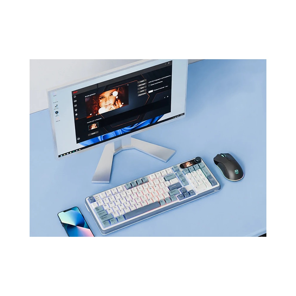 Jasne biurko z monitorem, biało-szarą klawiaturą, czarną myszką komputerową i smartfonem.