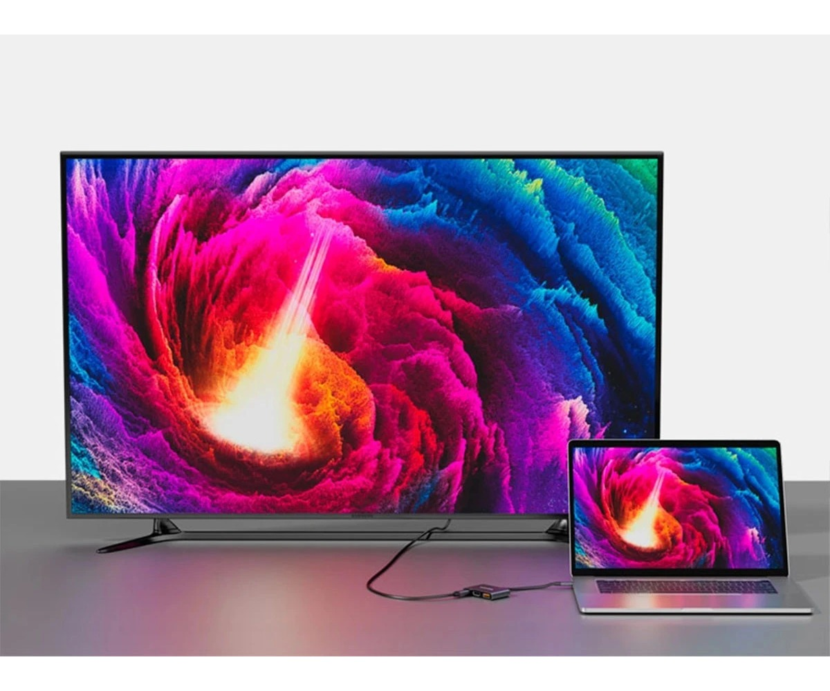 Laptop jest połączony kablem z dużym monitorem, oba wyświetlają kolorowy obraz abstrakcyjny.