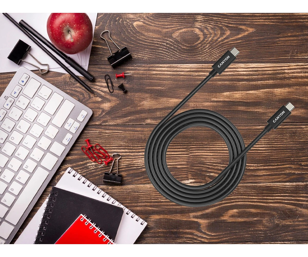 Czarny kabel Canyon USB-C na drewnianym biurku z klawiaturą, notatnikami i spinaczami.